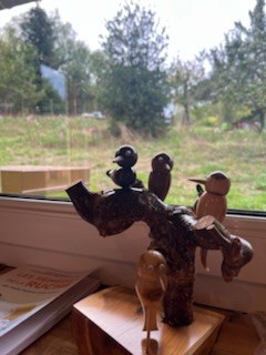 Oiseaux sculptés sur une branche, posés devant la fenêtre