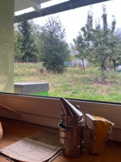 L'intérieur de la pièce curative en bois : la fenêtre donne sur le rucher, l'enfumoir posé sur le rebord